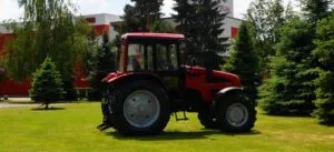 Red tractor on green lawn in front of an industrial building